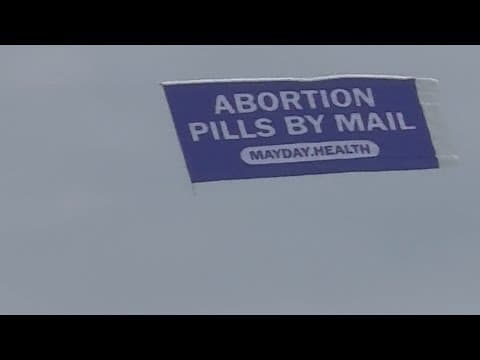 Thumbnail for 'Abortion pills' banner seen flying Saturday outside Globe Life Field